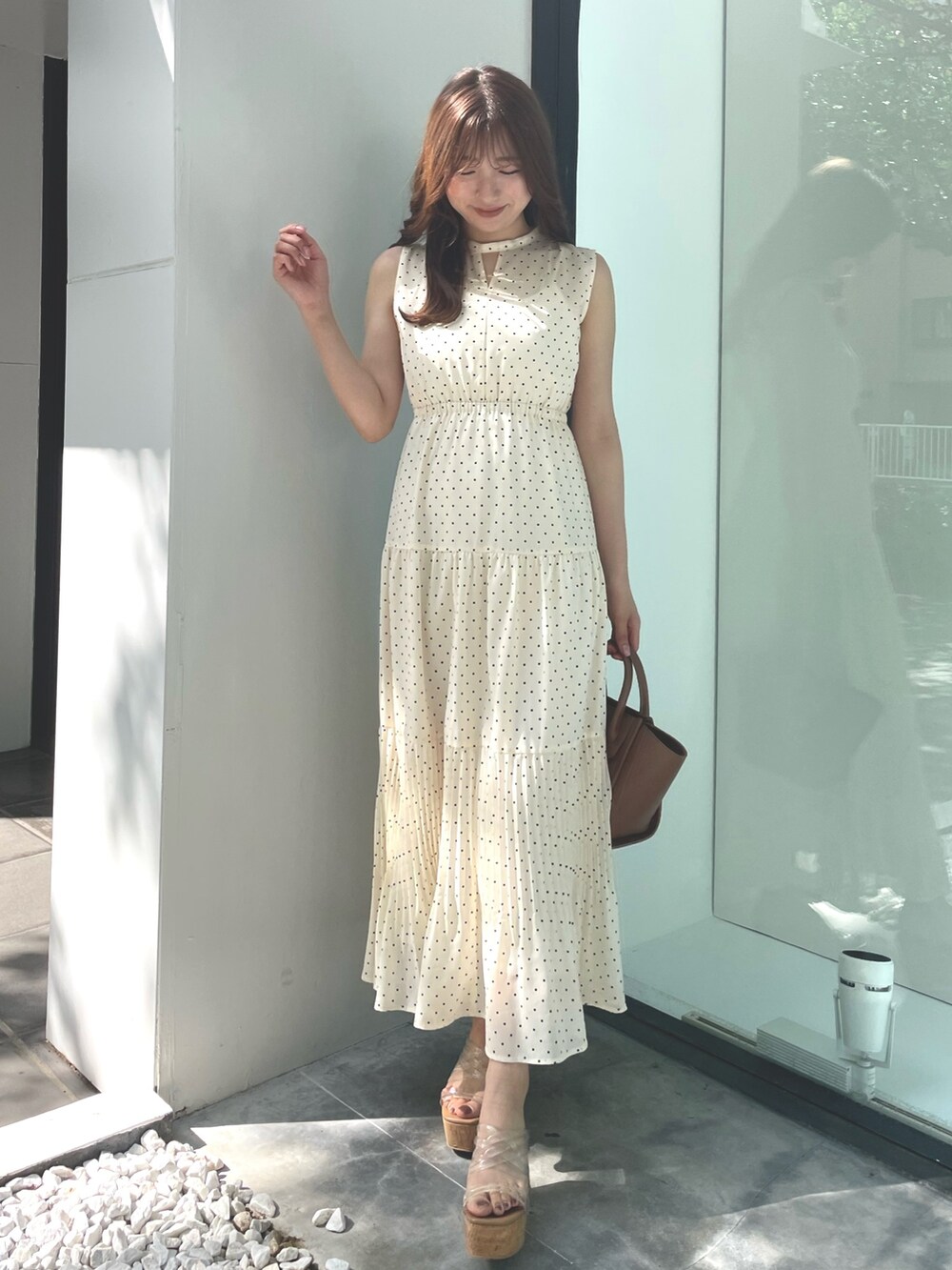 ベージュ系のワンピース、ブラウン系のトートバッグ、ホワイト系のサンダルを着用したレディースの夏コーディネートの2枚目の写真