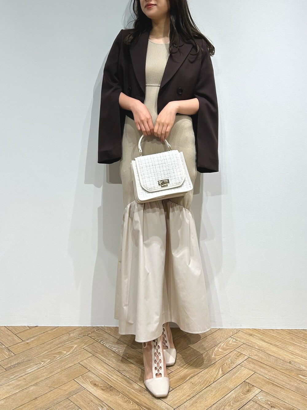 ブラウン系のテーラードジャケット、ベージュ系のワンピース、ホワイト系のブーツを着用したレディースの夏コーディネートの2枚目の写真