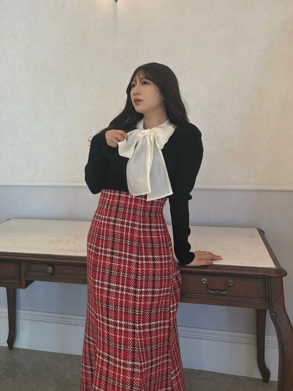 ブラック系のニット/セーター、レッド系のスカートを着用したレディースの秋コーディネートの3枚目の写真