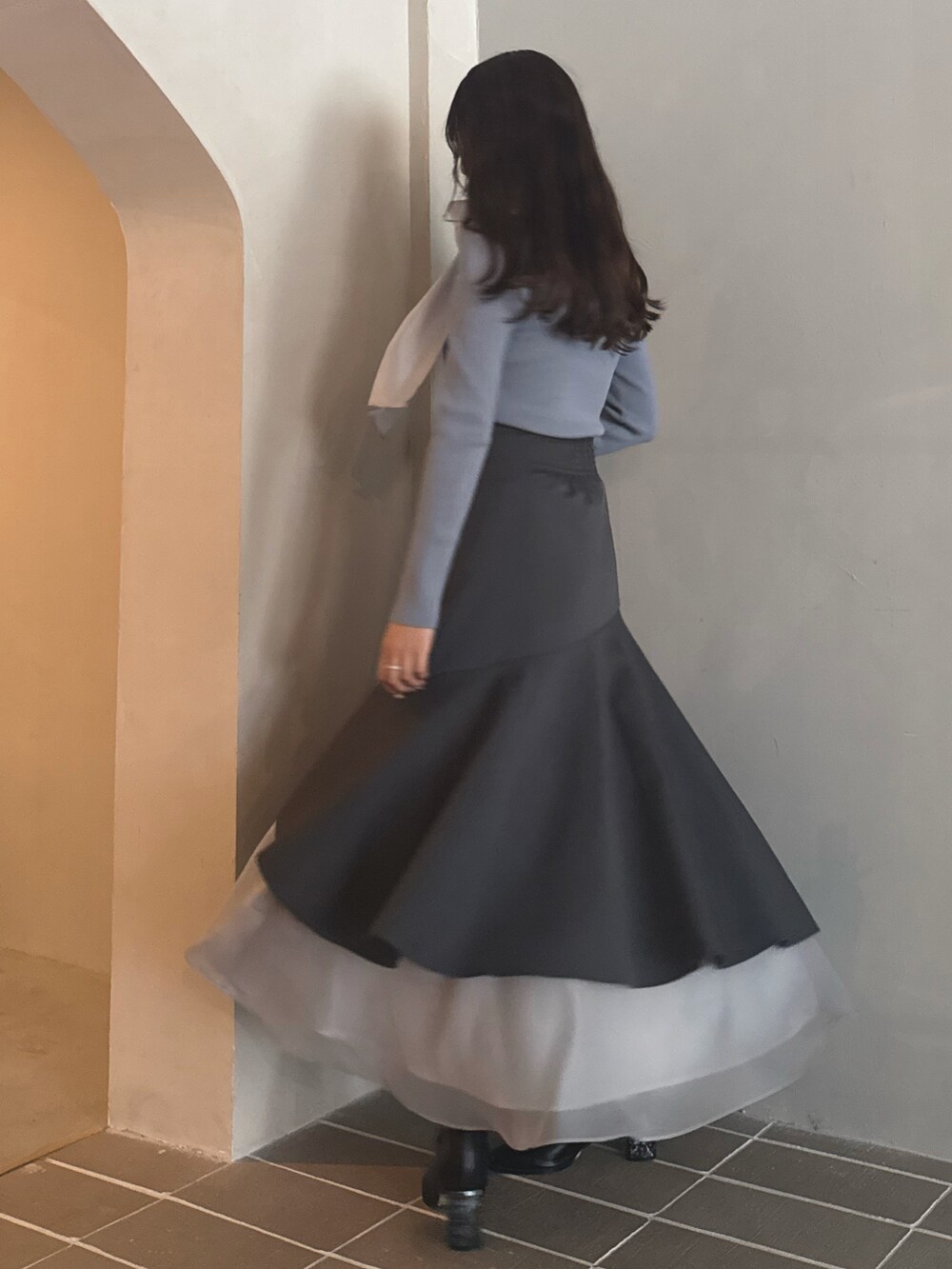 ブルー系のニット/セーター、グレー系のスカート、ブラック系のブーツを着用したレディースの秋コーディネートの3枚目の写真