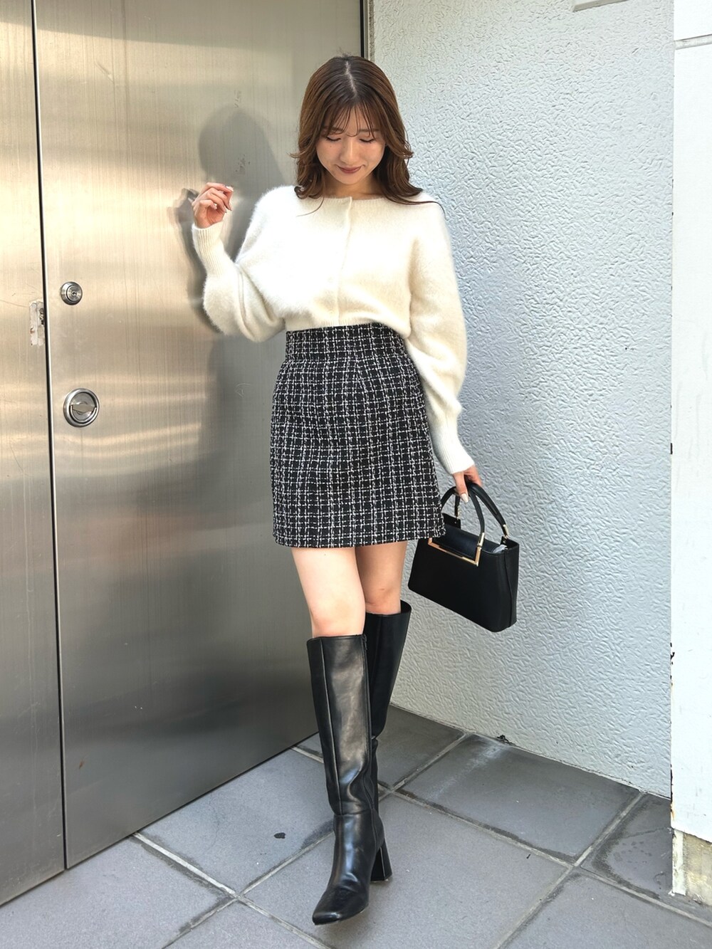 ホワイト系のカーディガン/ボレロ、ブラック系のスカート、ブラック系のブーツを着用したレディースの秋コーディネートの2枚目の写真