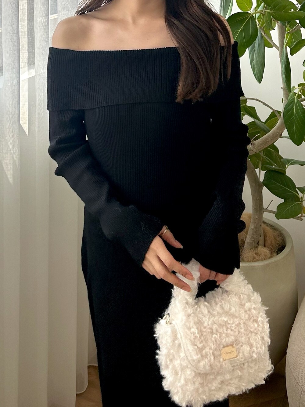 ブラック系のワンピース、ホワイト系のハンドバッグ、ブラック系のブーツを着用したレディースの秋コーディネートの2枚目の写真