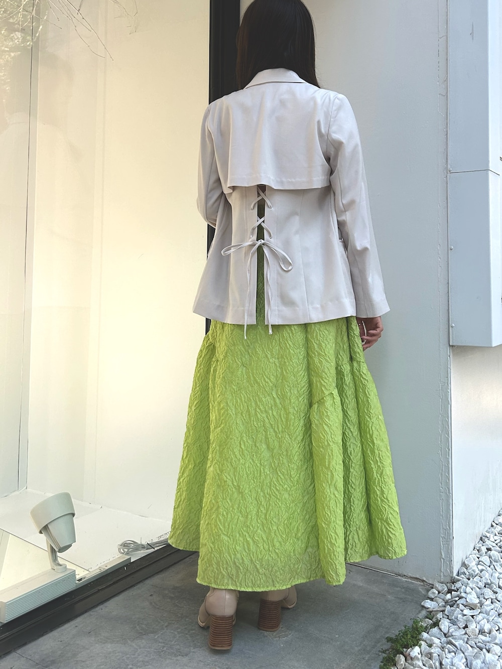 ホワイト系のニット/セーター、ホワイト系のテーラードジャケット、グリーン系のスカートを着用したレディースの春コーディネートの5枚目の写真
