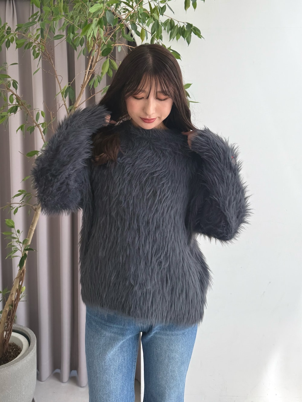 グレー系のニット/セーター、ブルー系のデニムパンツ、ブラウン系のブーツを着用したレディースの秋コーディネートの5枚目の写真