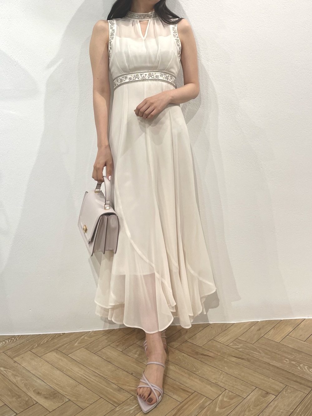 パープル系のサンダル、ホワイト系のドレス、パープル系のハンドバッグを着用したレディースの春コーディネートの2枚目の写真