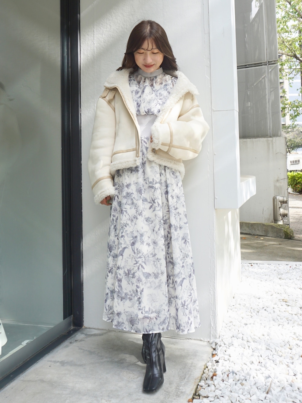 ブラック系のブーツ、ホワイト系のムートンコート、グレー系のワンピースを着用したレディースの冬コーディネートの4枚目の写真