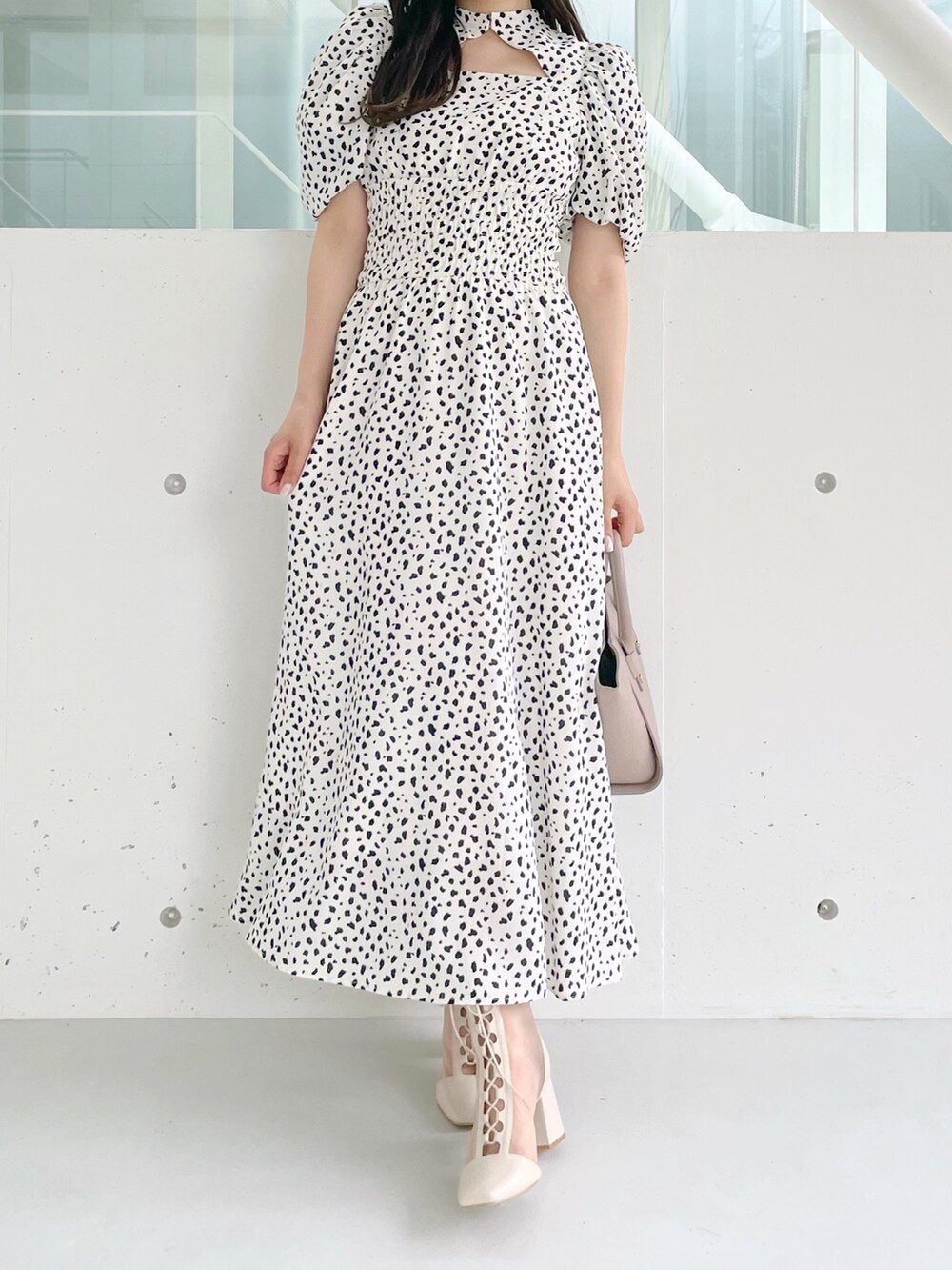 ホワイト系のワンピース、ベージュ系のハンドバッグ、ホワイト系のブーツを着用したレディースの夏コーディネートの2枚目の写真