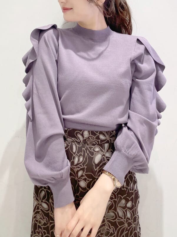 パープル系のニット/セーター、ベージュ系のハンドバッグ、ブラウン系のスカートを着用したレディースの冬コーディネートの4枚目の写真