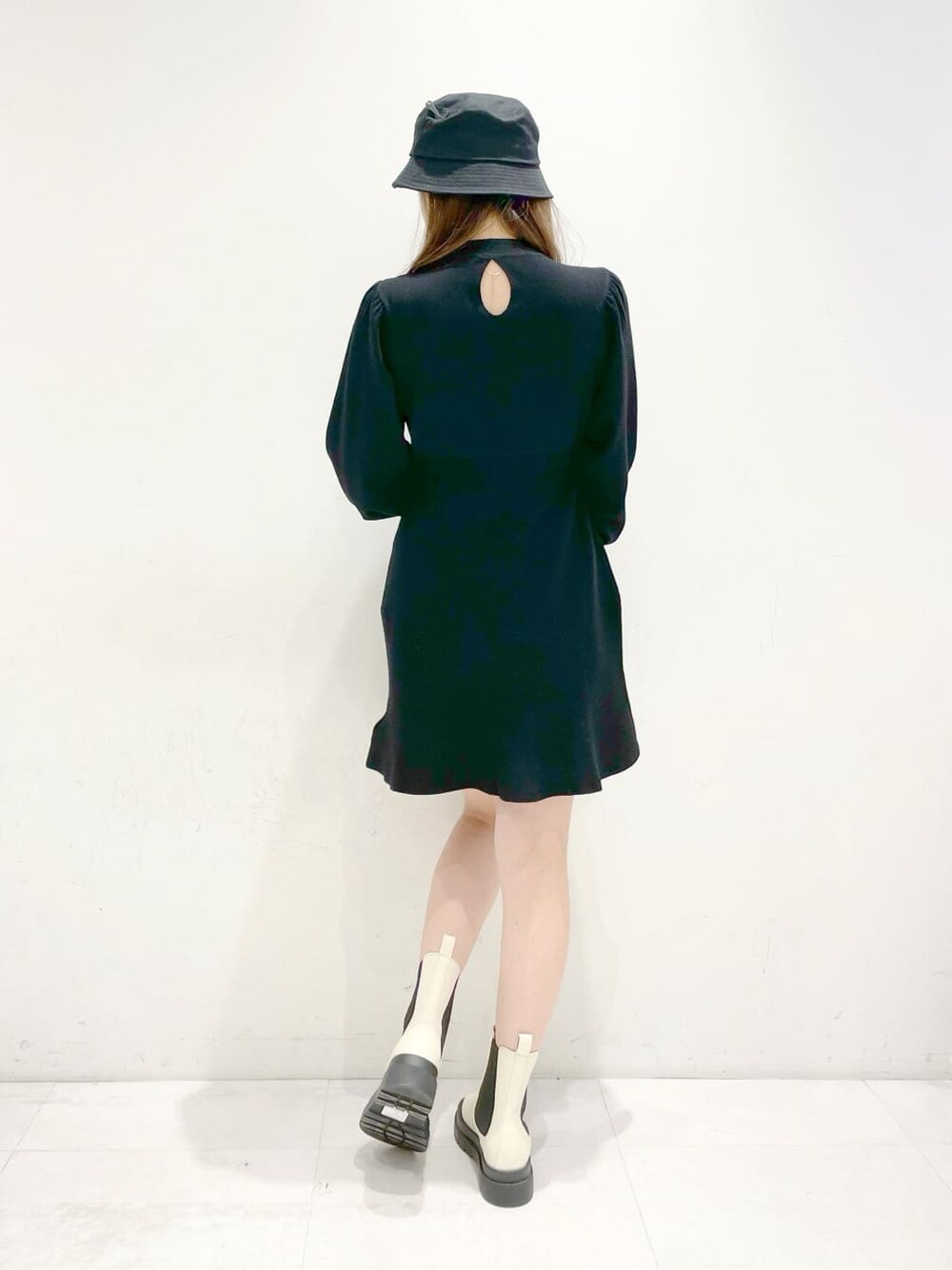 ホワイト系のブーツ、ブラック系のワンピース、ブラック系のハットを着用したレディースの冬コーディネートの3枚目の写真