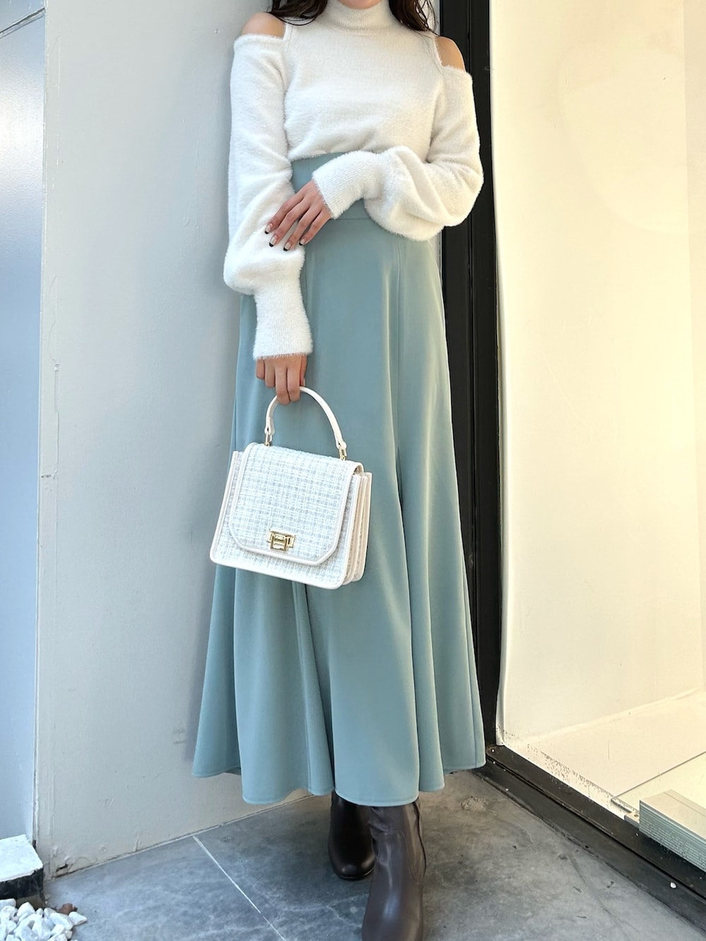 ホワイト系のニット/セーター、グリーン系のスカート、ホワイト系のショルダーバッグを着用したレディースの冬コーディネートの2枚目の写真