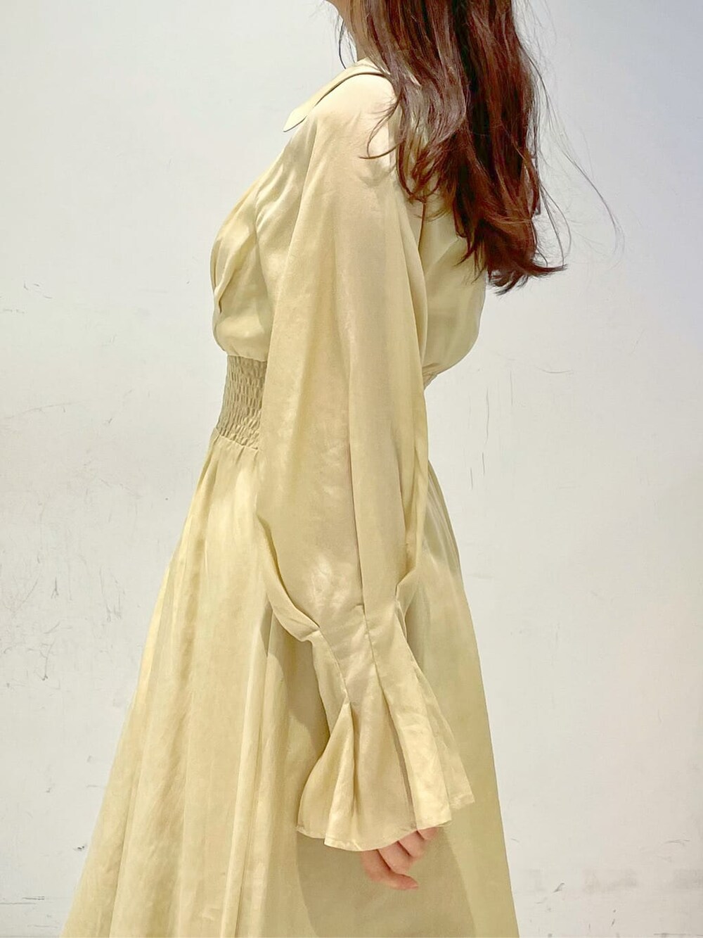 イエロー系のワンピース、ブラウン系のパンプスを着用したレディースの冬コーディネートの5枚目の写真