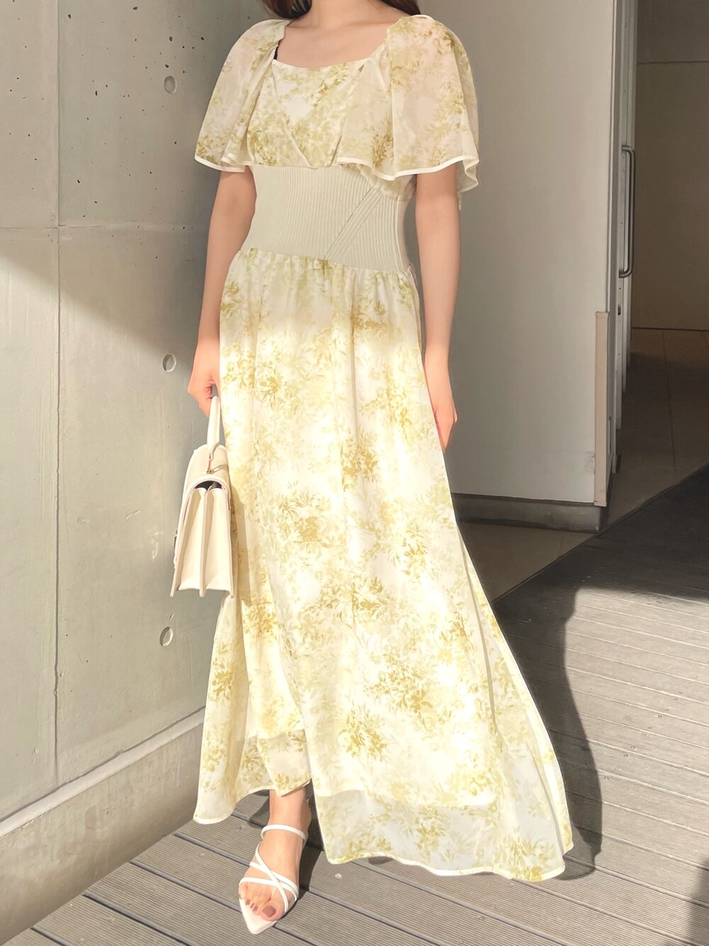 ホワイト系のハンドバッグ、イエロー系のワンピース、ホワイト系のサンダルを着用したレディースの春コーディネートの2枚目の写真