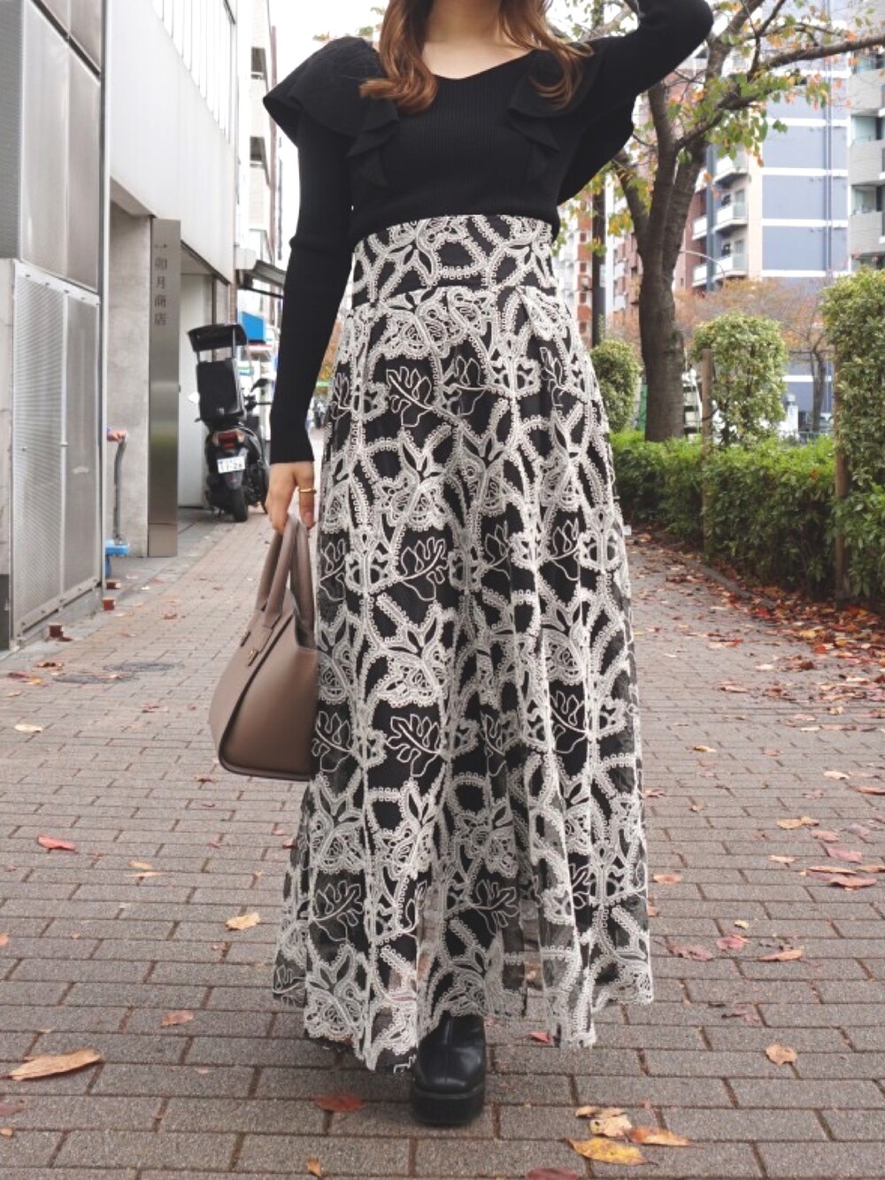 ブラック系のブーツ、ベージュ系のハンドバッグ、ブラック系のスカートを着用したレディースの冬コーディネートの4枚目の写真