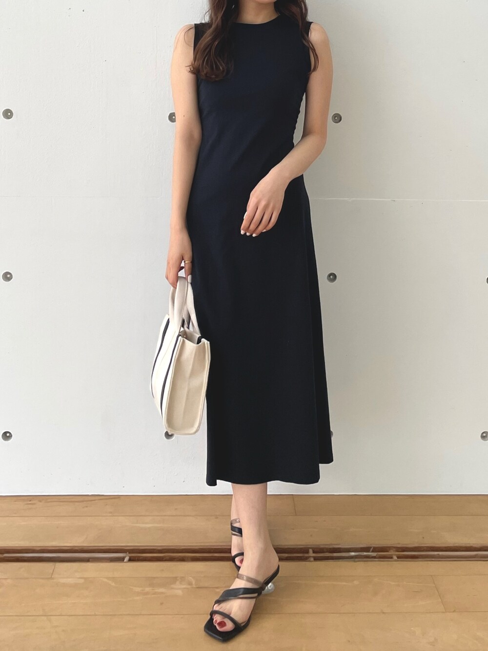ブラック系のワンピース、ホワイト系のハンドバッグ、ブラック系のサンダルを着用したレディースの春コーディネートの2枚目の写真