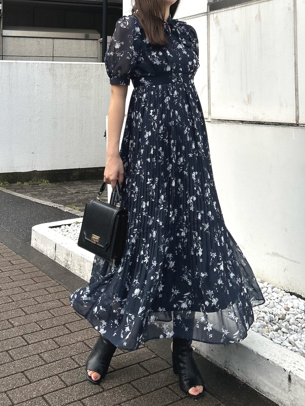 ブルー系のワンピース、ブラック系のブーツ、ブラック系のハンドバッグを着用したレディースの春コーディネートの2枚目の写真