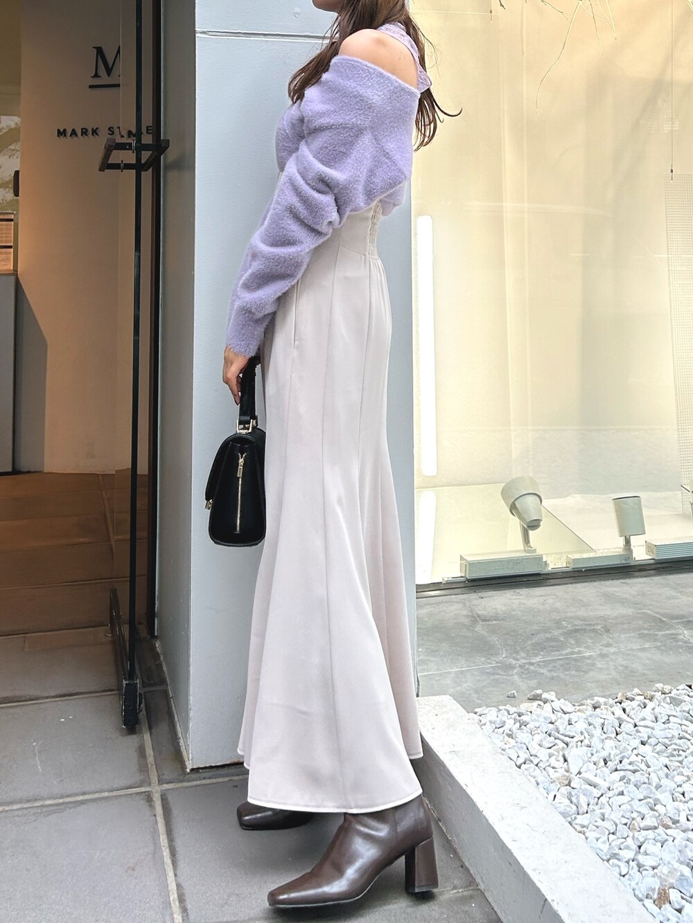 パープル系のニット/セーター、ホワイト系のスカート、ブラック系のショルダーバッグを着用したレディースの冬コーディネートの2枚目の写真