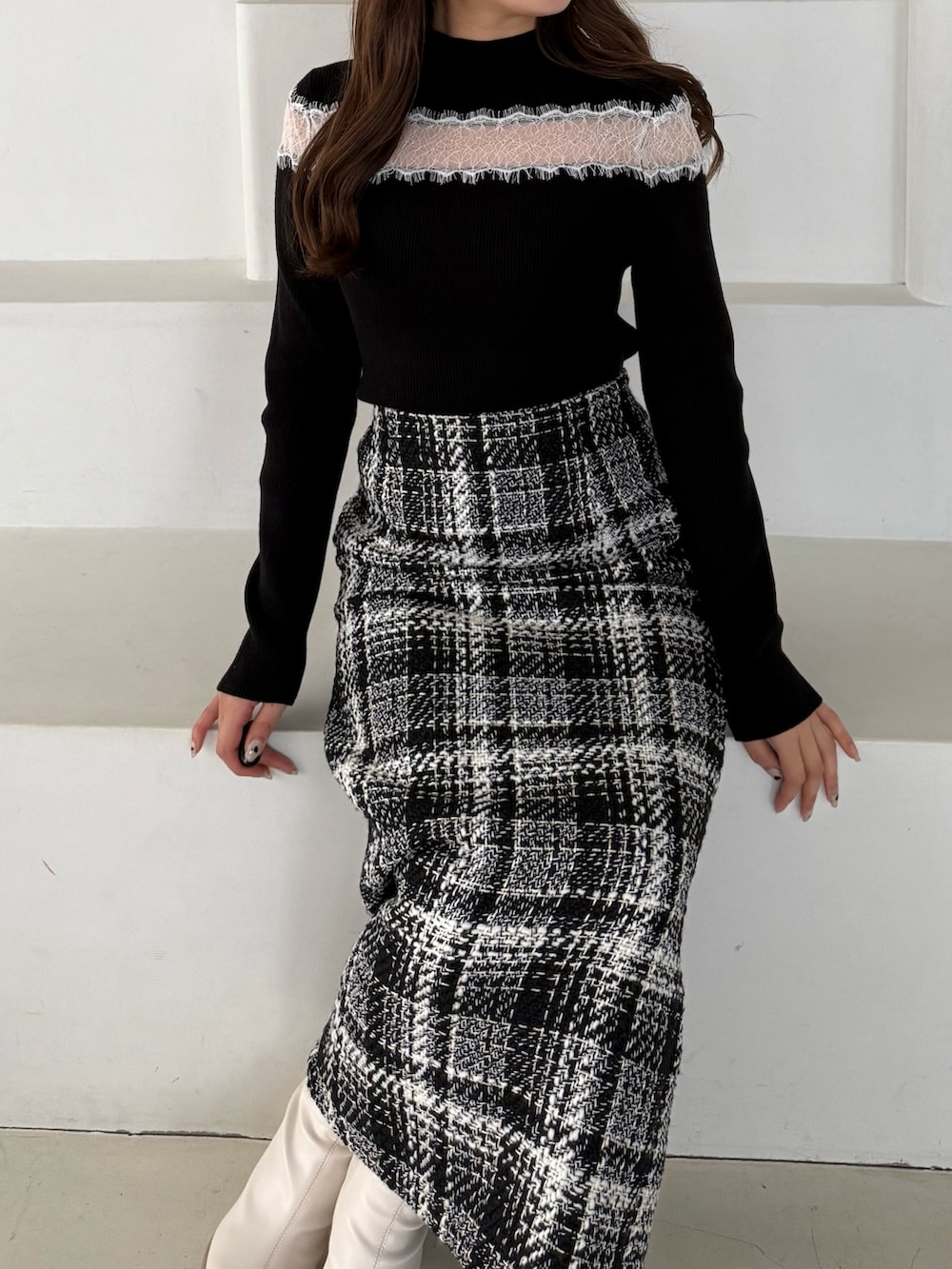 ブラック系のニット/セーター、ブラック系のスカート、ホワイト系のブーツを着用したレディースの秋コーディネートの4枚目の写真