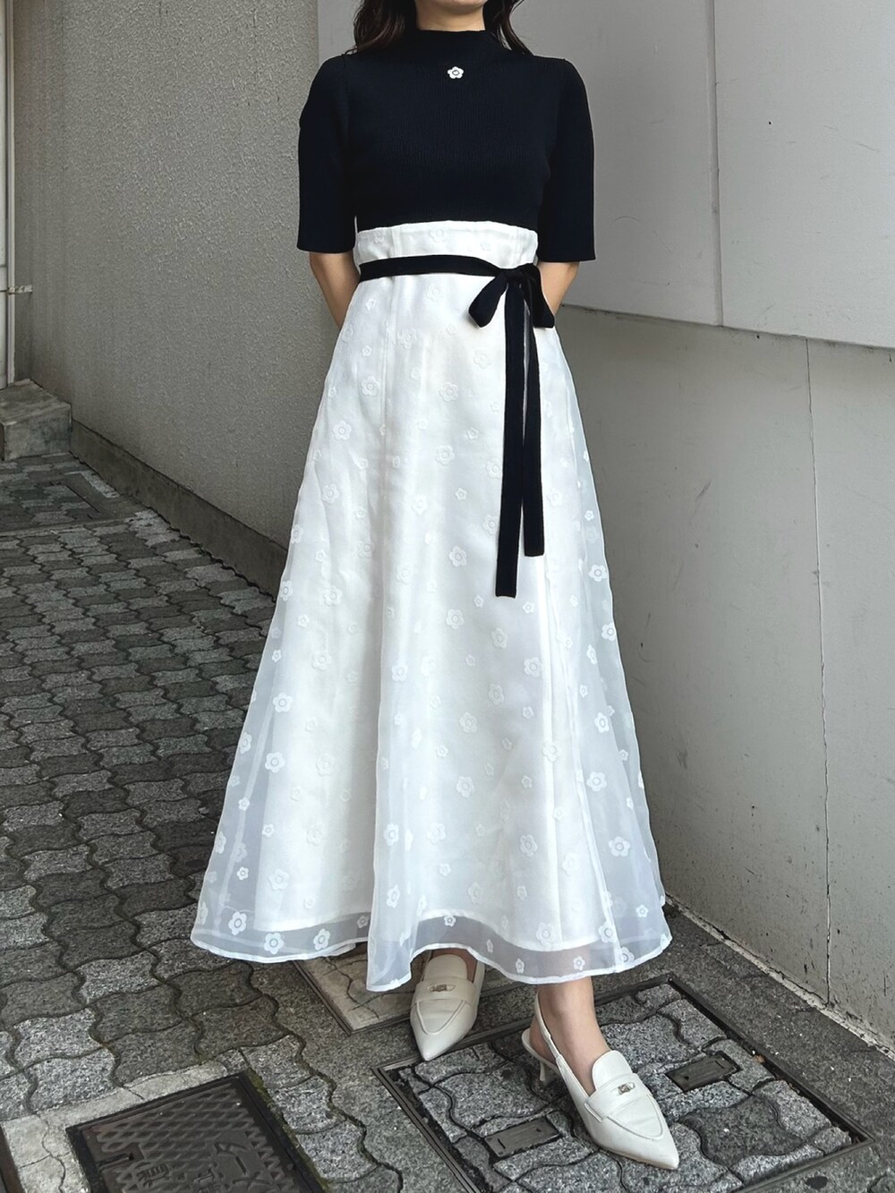 ブラック系のワンピース、ホワイト系のパンプス、パープル系のトレンチコートを着用したレディースの冬コーディネートの3枚目の写真