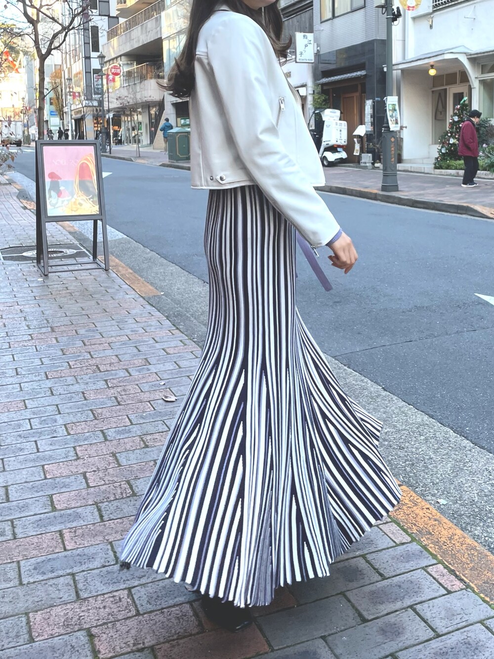 パープル系のワンピース、ホワイト系のライダースジャケットを着用したレディースの冬コーディネートの6枚目の写真