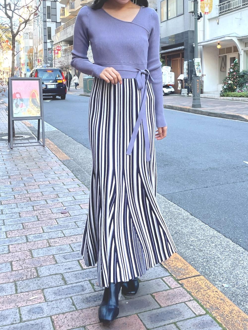 パープル系のワンピース、ホワイト系のライダースジャケットを着用したレディースの冬コーディネートの2枚目の写真