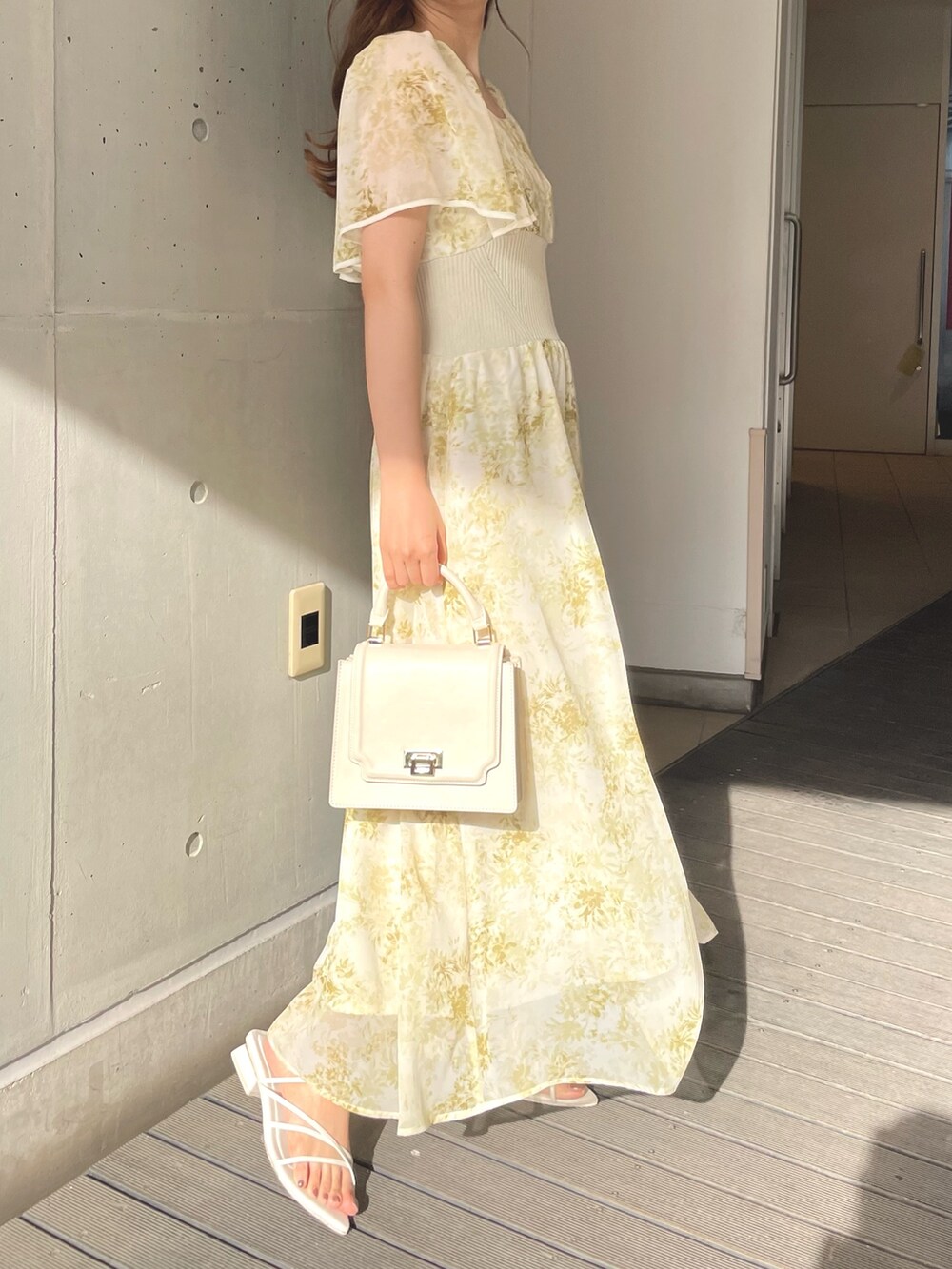 ホワイト系のハンドバッグ、イエロー系のワンピース、ホワイト系のサンダルを着用したレディースの春コーディネートの4枚目の写真
