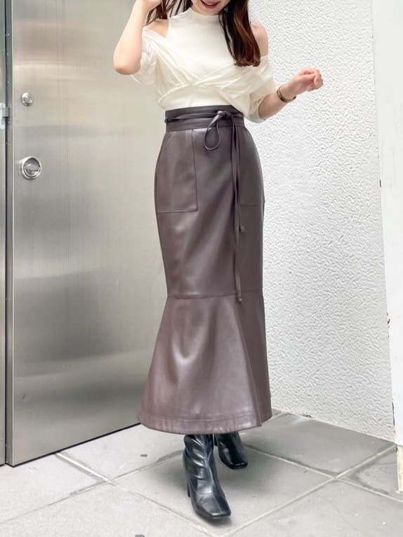 ブラック系のブーツ、ブラウン系のスカート、ホワイト系のニット/セーターを着用したレディースの夏コーディネートの2枚目の写真