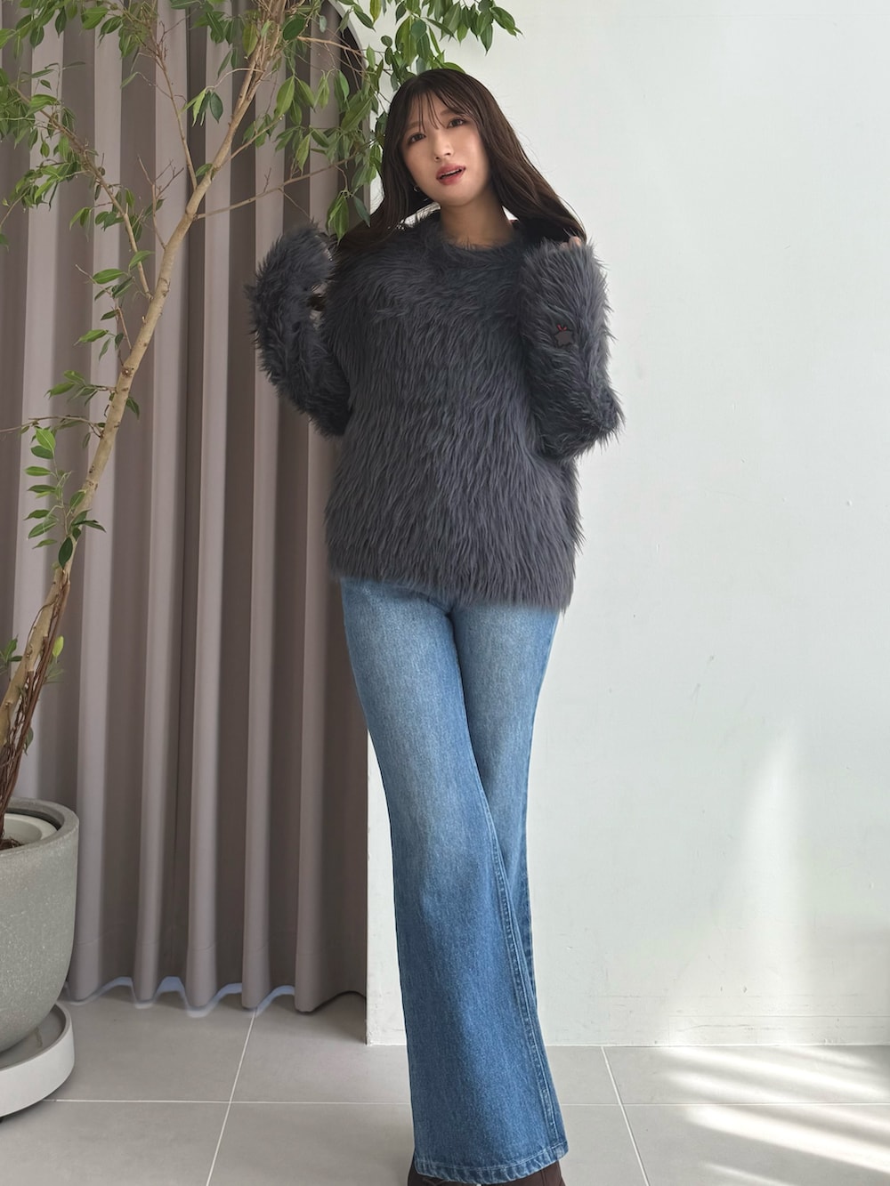 グレー系のニット/セーター、ブルー系のデニムパンツ、ブラウン系のブーツを着用したレディースの秋コーディネートの3枚目の写真