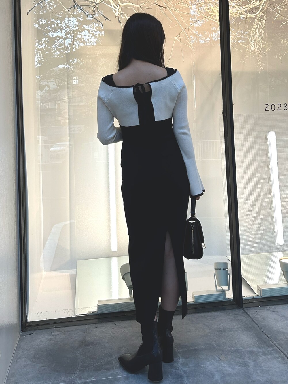 ブラック系のワンピース、ブラック系のショルダーバッグ、ブラック系のブーツを着用したレディースの秋コーディネートの4枚目の写真