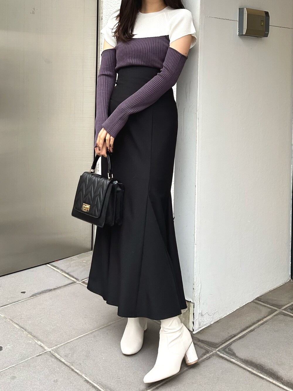 グレー系のニット/セーター、ブラック系のスカート、ブラック系のショルダーバッグを着用したレディースの冬コーディネートの3枚目の写真