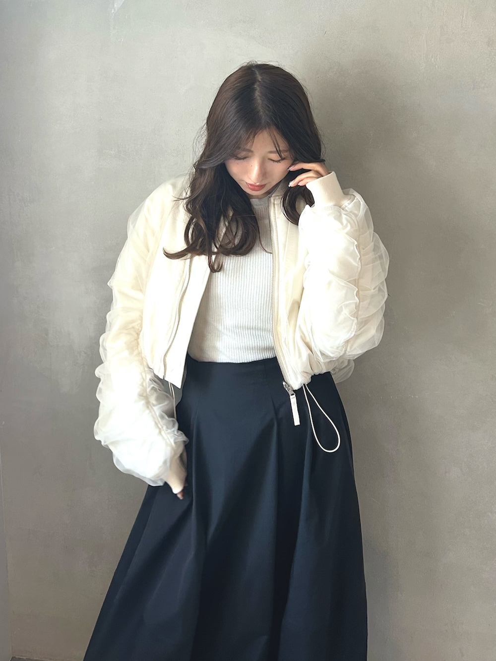 グレー系のニット/セーター、ホワイト系のMA-1、ブラック系のスカートを着用したレディースの春コーディネートの3枚目の写真