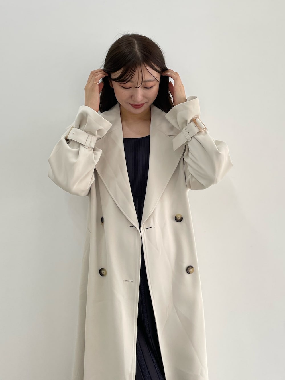 グレー系のワンピース、ホワイト系のトレンチコートを着用したレディースの冬コーディネートの7枚目の写真