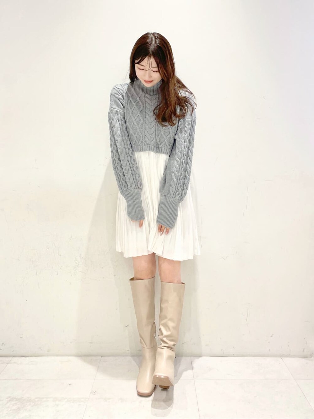 ブラウン系のブルゾン、ベージュ系のブーツ、グレー系のワンピースを着用したレディースの冬コーディネートの4枚目の写真