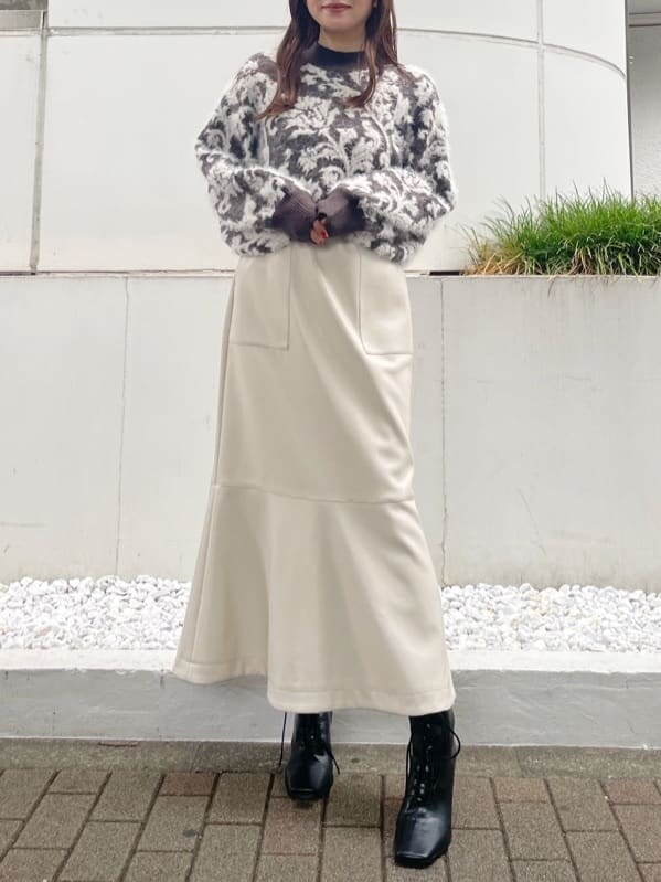ブラウン系のニット/セーター、ブラック系のブーツ、ホワイト系のスカートを着用したレディースの秋コーディネートの2枚目の写真