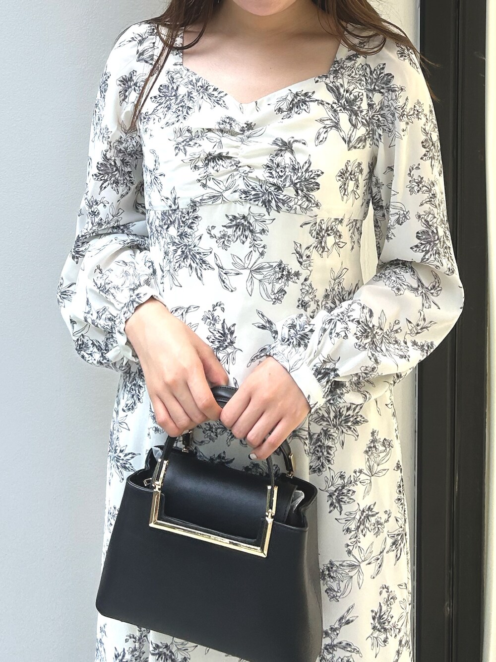 ブラック系のハンドバッグ、ホワイト系のワンピースを着用したレディースの夏コーディネートの4枚目の写真