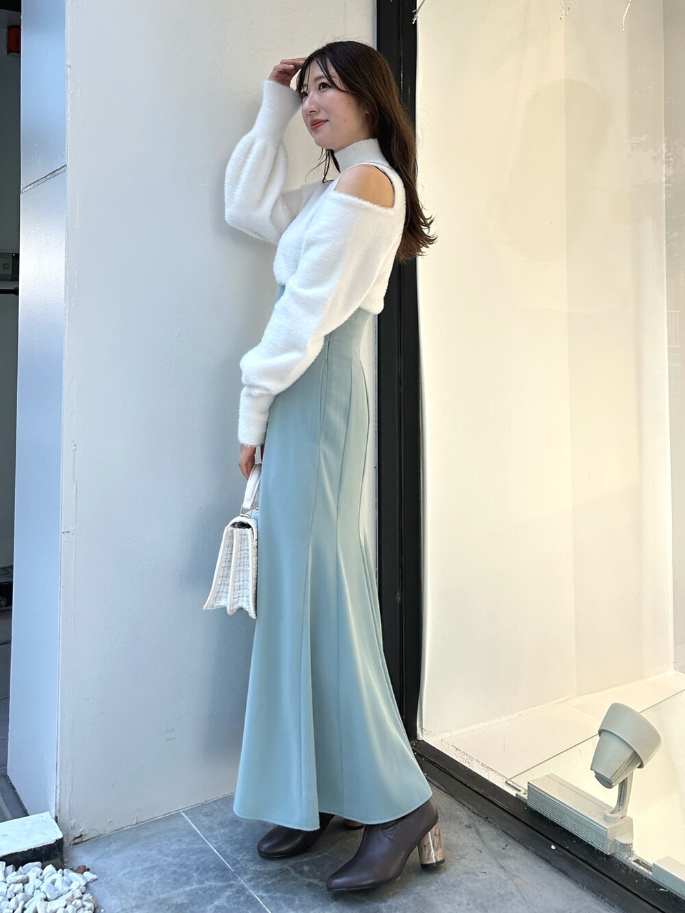 ホワイト系のニット/セーター、グリーン系のスカート、ホワイト系のショルダーバッグを着用したレディースの冬コーディネートの3枚目の写真