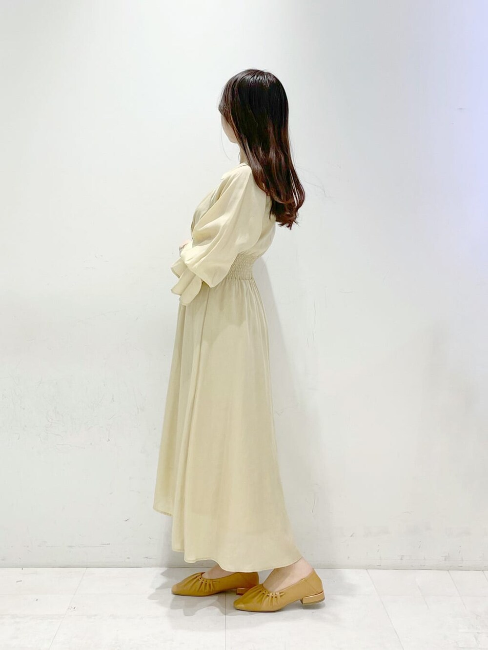 イエロー系のワンピース、ブラウン系のパンプスを着用したレディースの冬コーディネートの3枚目の写真