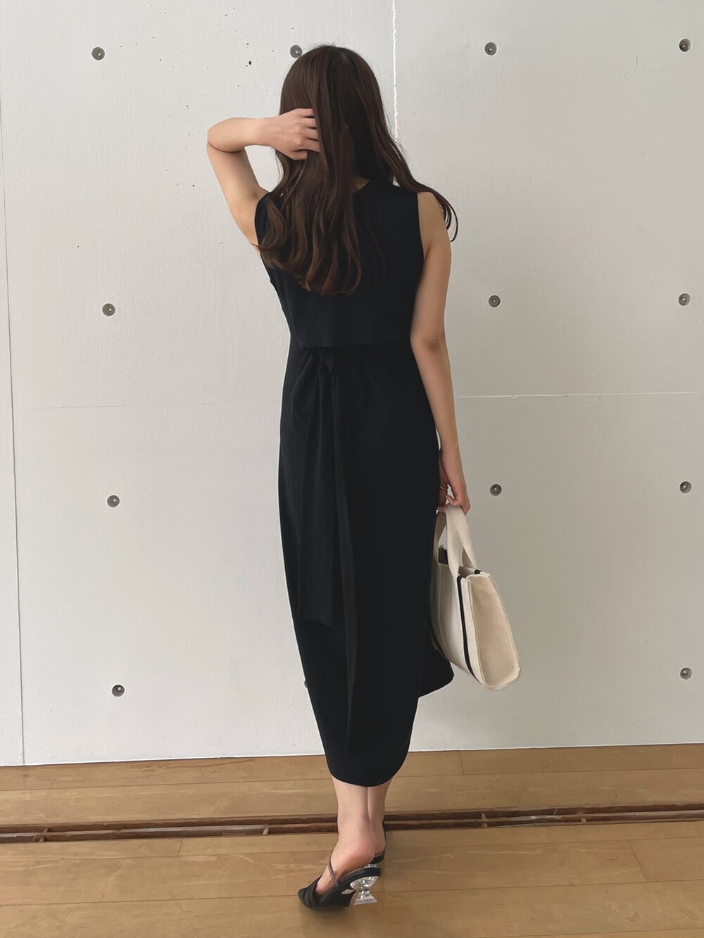 ブラック系のワンピース、ホワイト系のハンドバッグ、ブラック系のサンダルを着用したレディースの春コーディネートの3枚目の写真