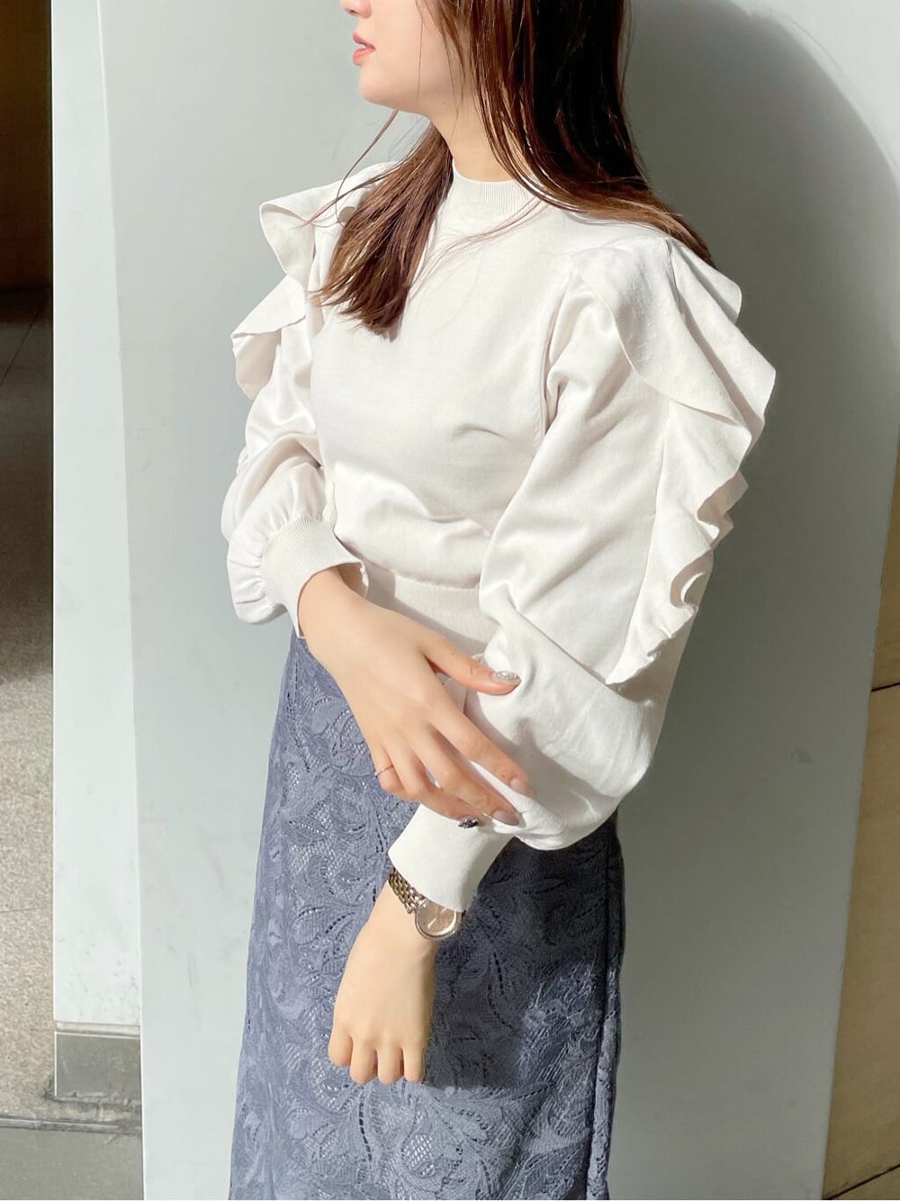 ホワイト系のチェスターコート、ホワイト系のニット/セーター、ブルー系のスカートを着用したレディースの冬コーディネートの6枚目の写真