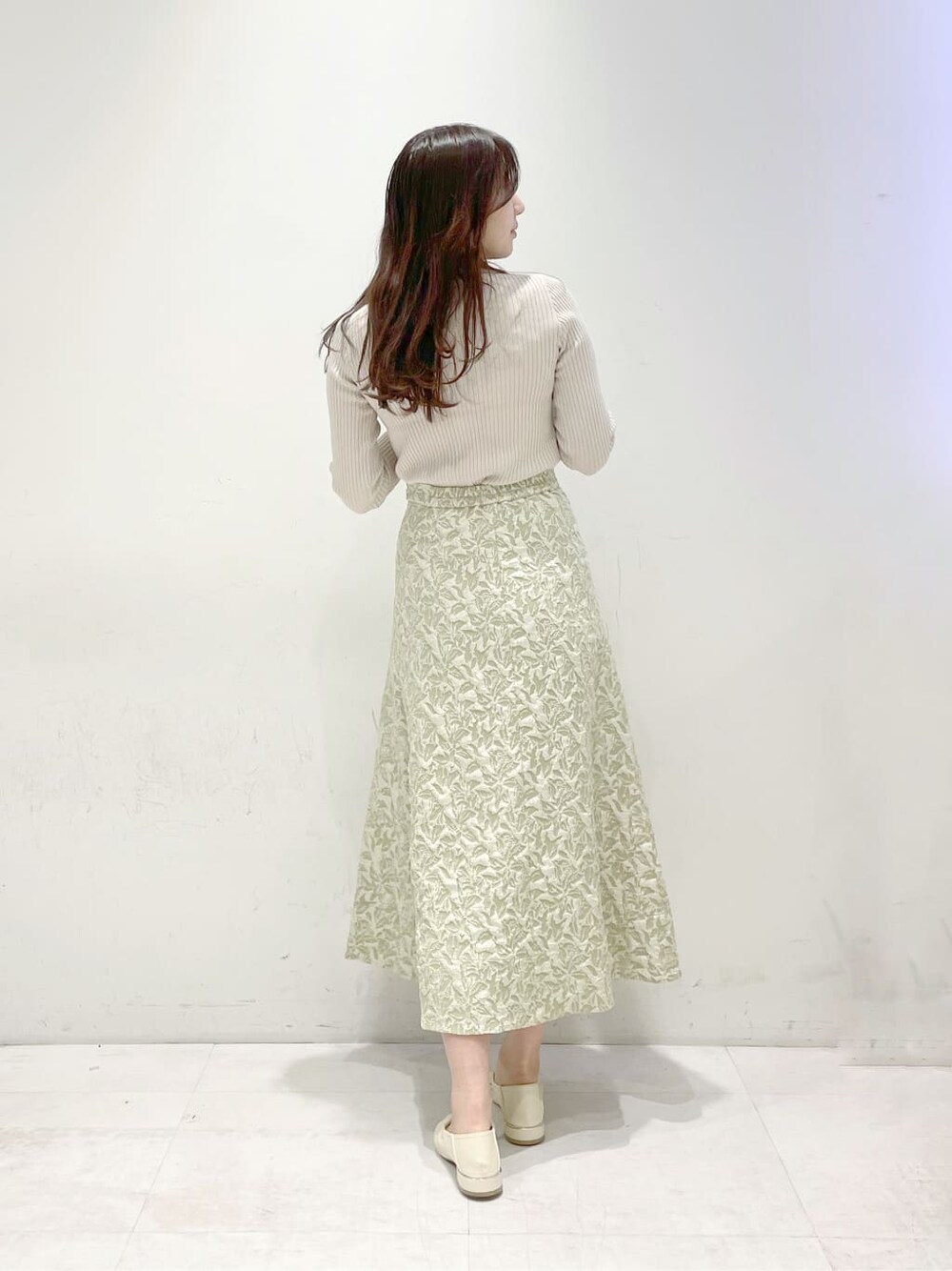 グリーン系のスカート、ホワイト系のパンプス、ベージュ系のニット/セーターを着用したレディースの冬コーディネートの3枚目の写真