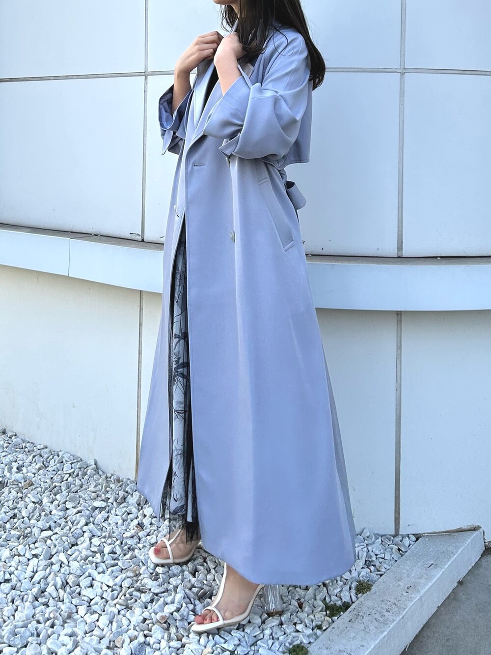 ブルー系のトレンチコート、ブラック系のワンピース、ホワイト系のブーツを着用したレディースの冬コーディネートの2枚目の写真