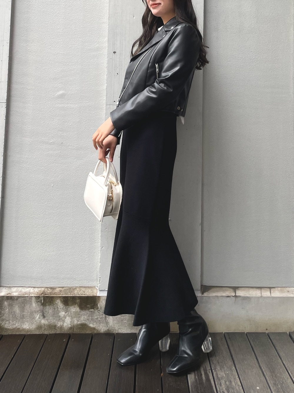 ブラック系のワンピース、ホワイト系のハンドバッグ、ブラック系のブーツを着用したレディースの冬コーディネートの6枚目の写真