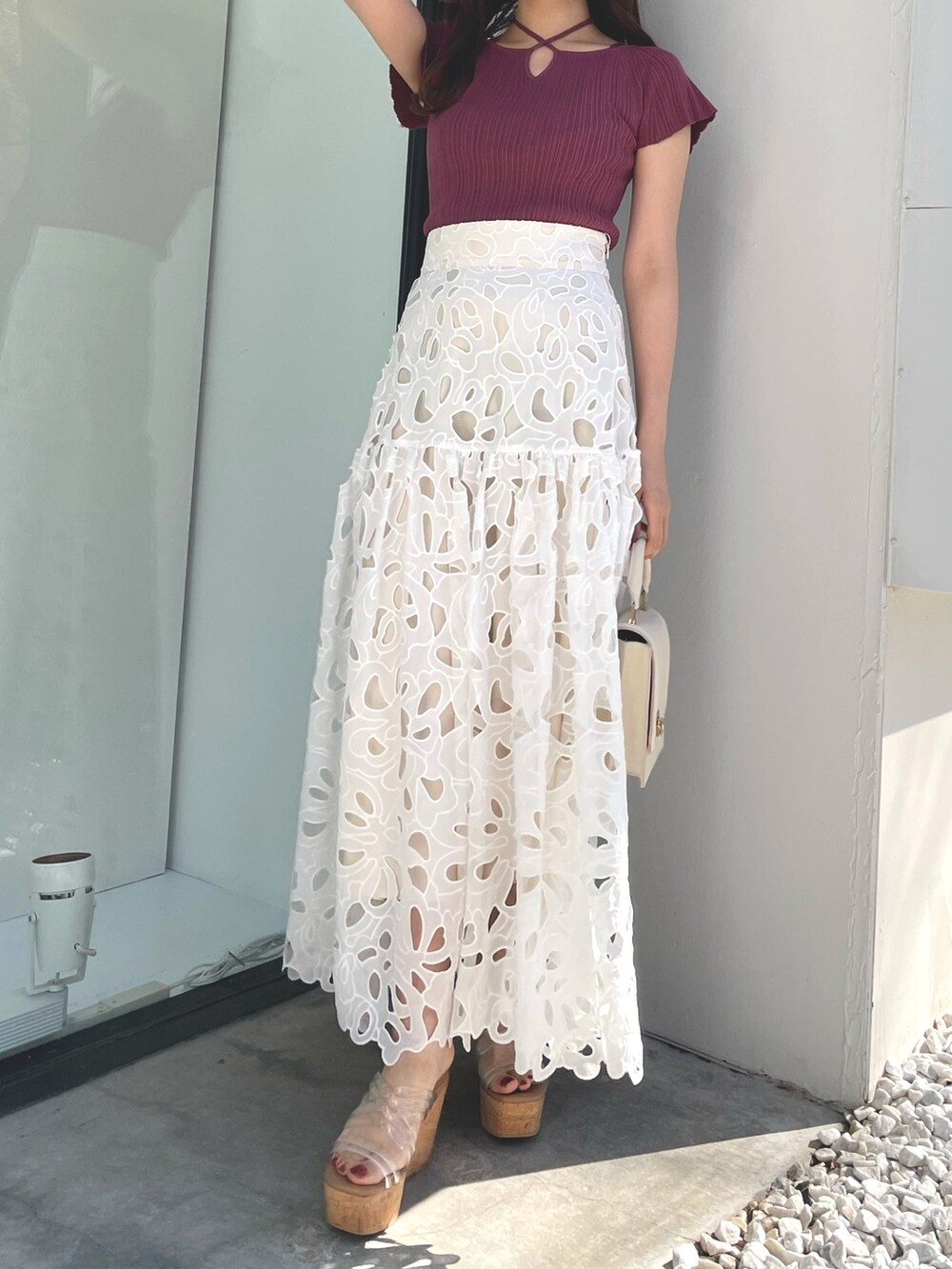 ピンク系のニット/セーター、ホワイト系のハンドバッグ、ホワイト系のスカートを着用したレディースの春コーディネートの3枚目の写真