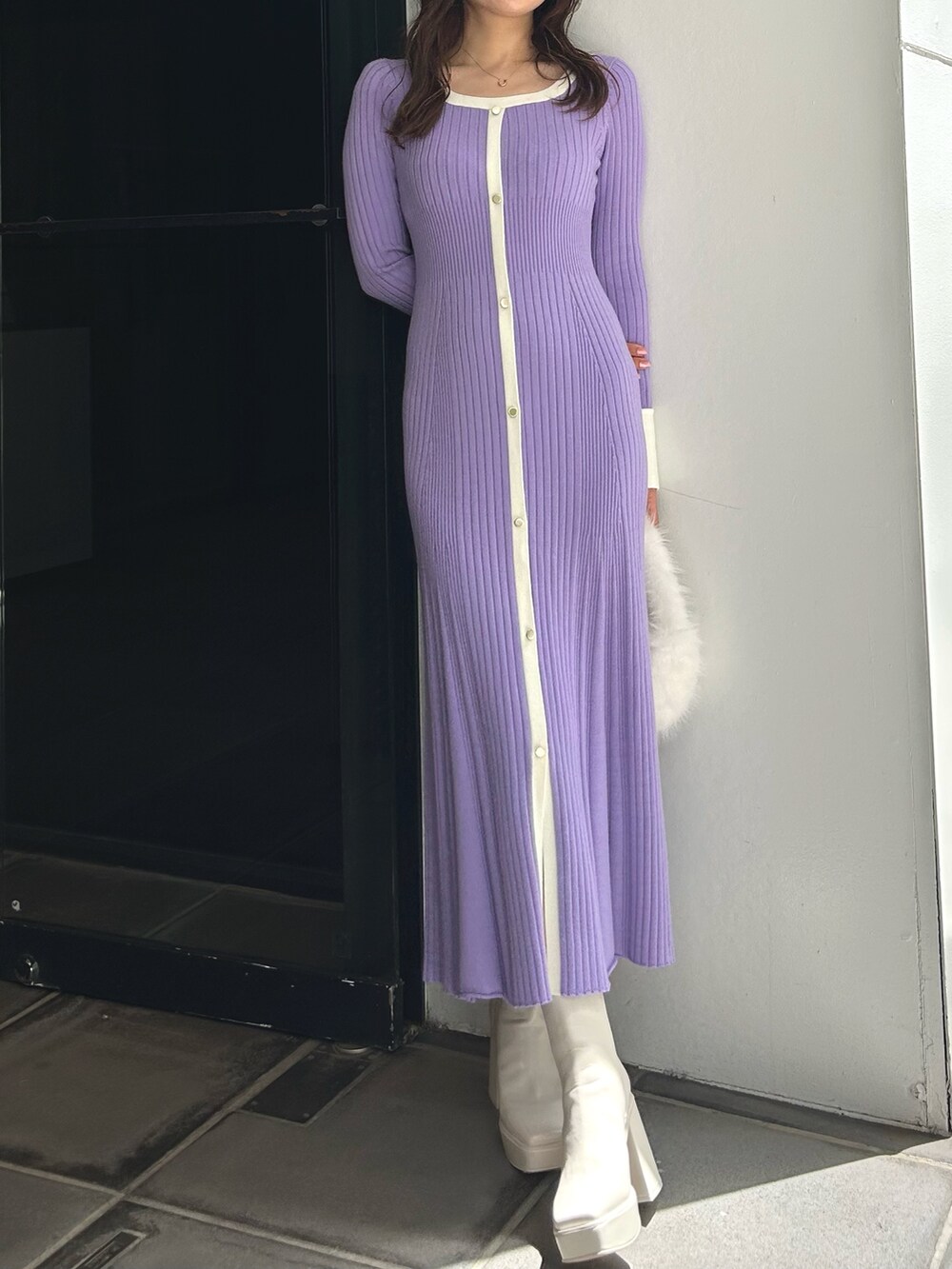 ホワイト系のハンドバッグ、ホワイト系のブーツ、パープル系のワンピースを着用したレディースの冬コーディネートの2枚目の写真