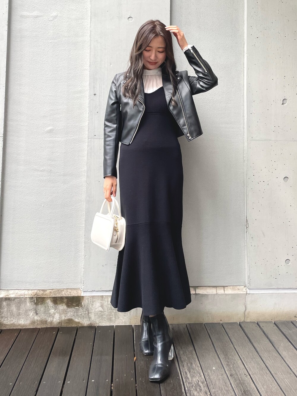 ブラック系のワンピース、ホワイト系のハンドバッグ、ブラック系のブーツを着用したレディースの冬コーディネートの5枚目の写真