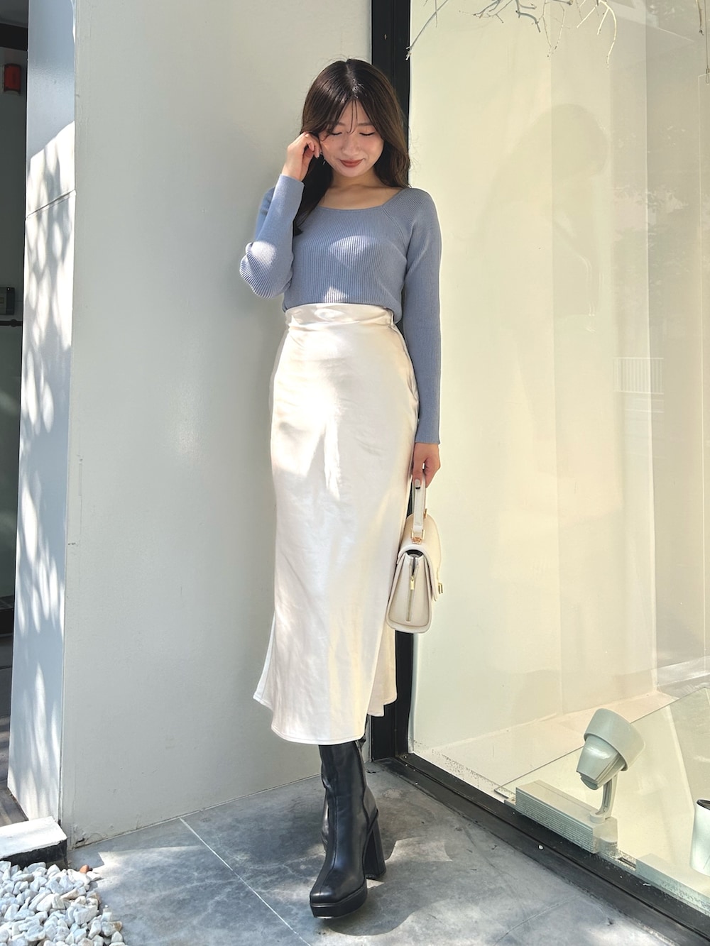 ブルー系のニット/セーター、ホワイト系のスカート、ブラック系のブーツを着用したレディースの秋コーディネートの2枚目の写真