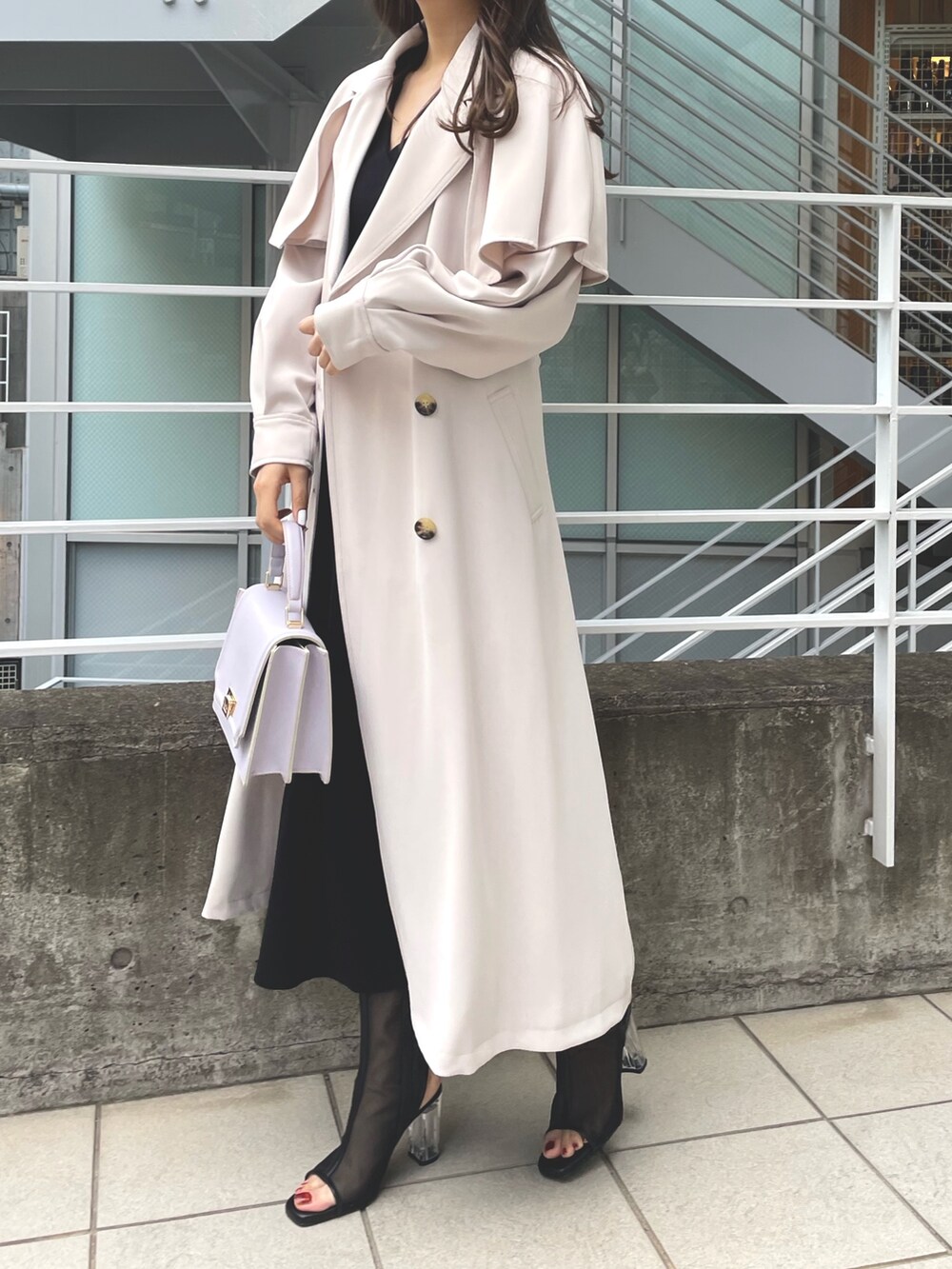 ピンク系のトレンチコート、グレー系のワンピース、パープル系のハンドバッグを着用したレディースの春コーディネートの2枚目の写真