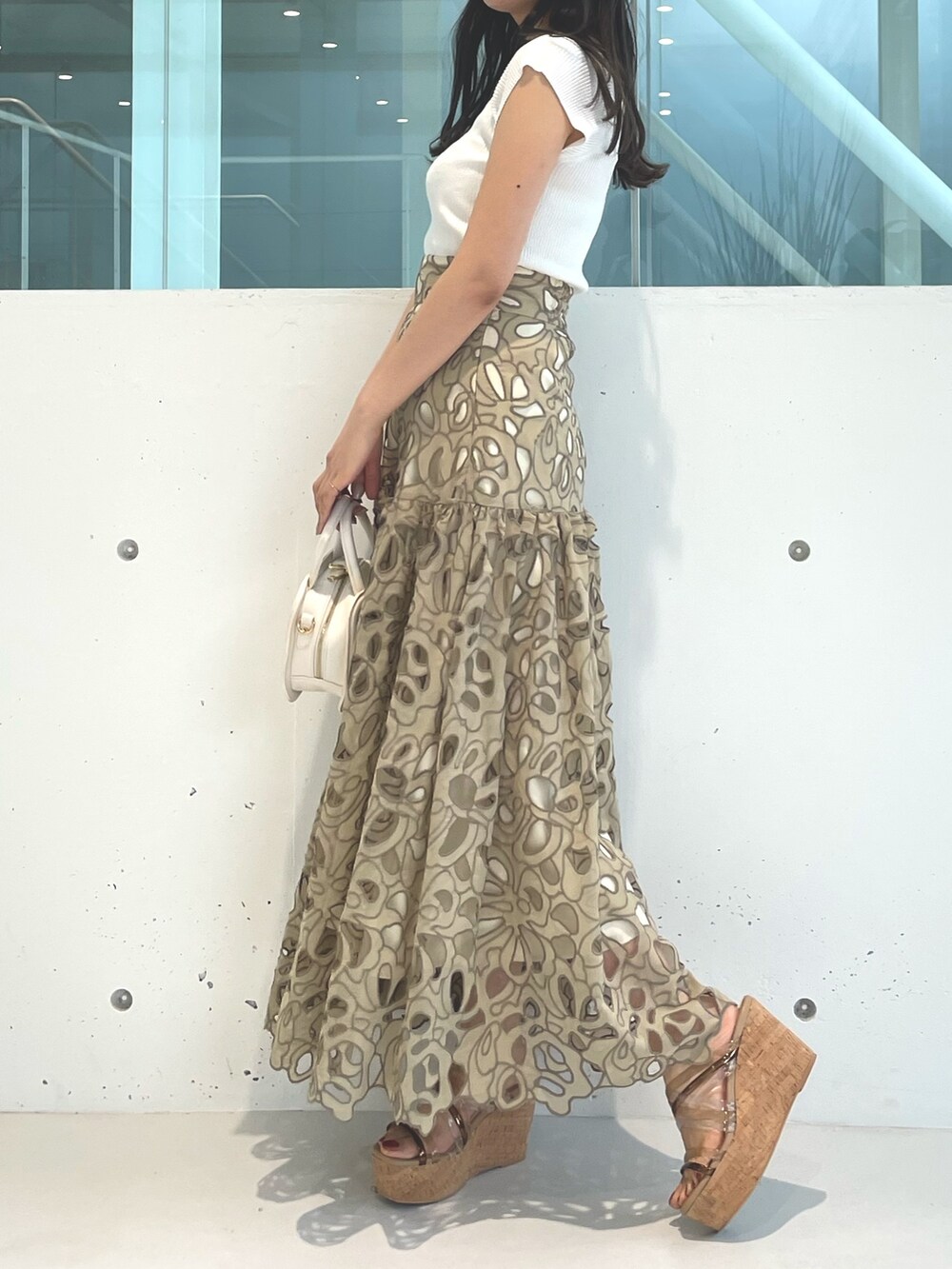 ホワイト系のニット/セーター、ブラウン系のサンダル、イエロー系のスカートを着用したレディースの春コーディネートの2枚目の写真