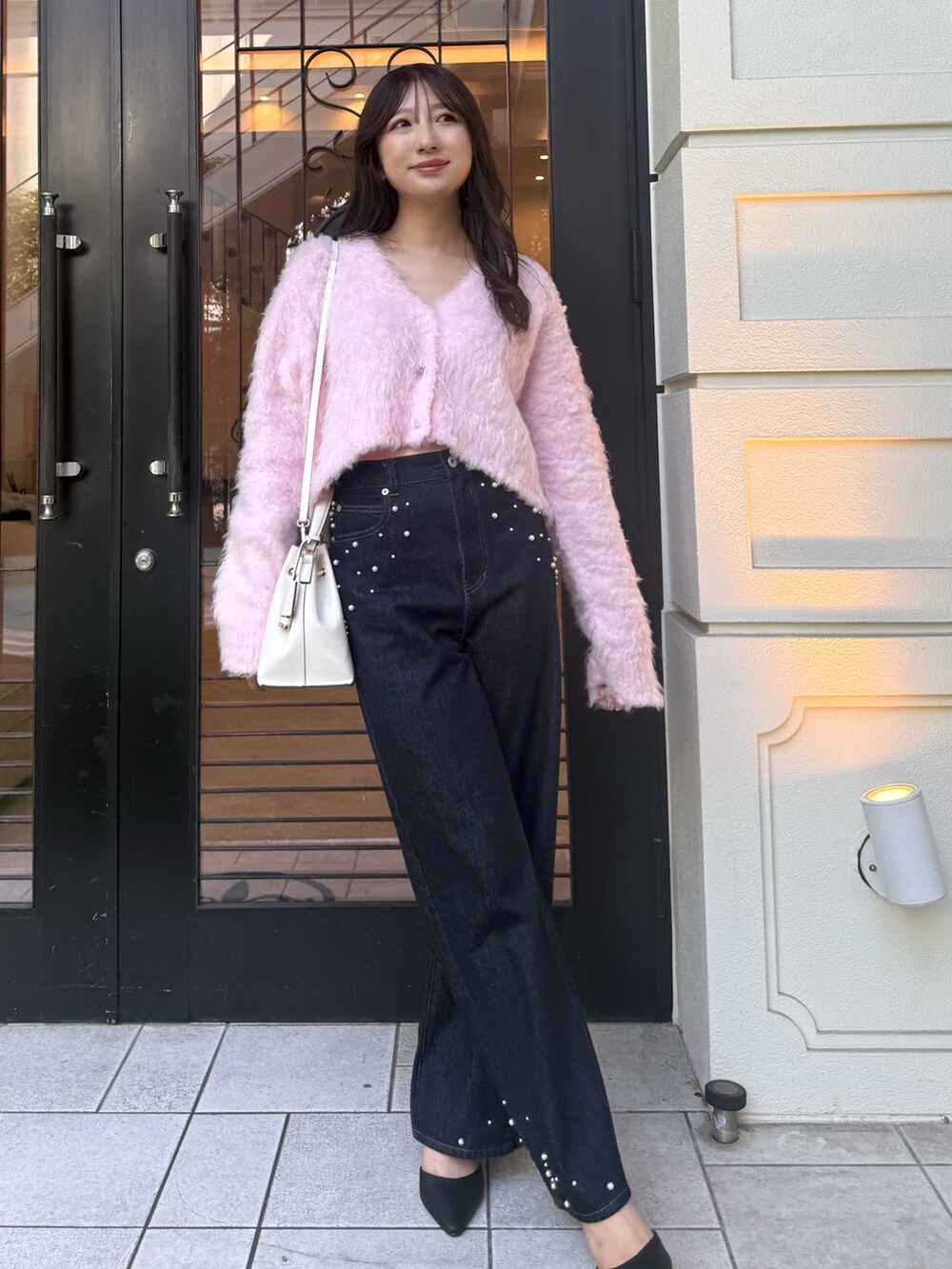 ピンク系のカーディガン/ボレロ、ブルー系のデニムパンツ、ブラック系のパンプスを着用したレディースの秋コーディネートの2枚目の写真