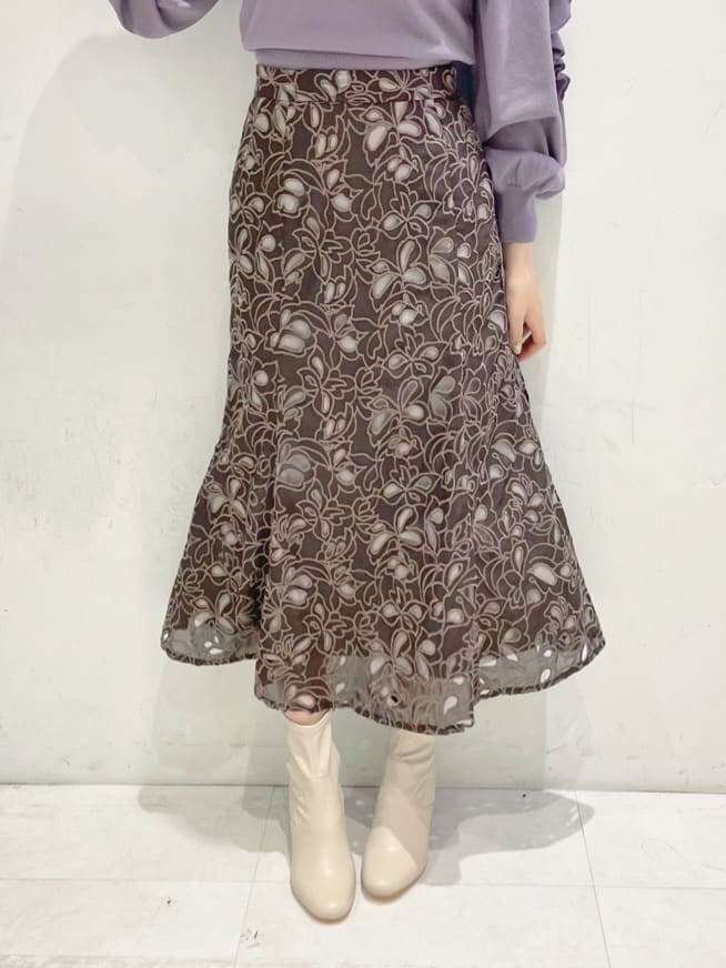 パープル系のニット/セーター、ベージュ系のハンドバッグ、ブラウン系のスカートを着用したレディースの冬コーディネートの7枚目の写真