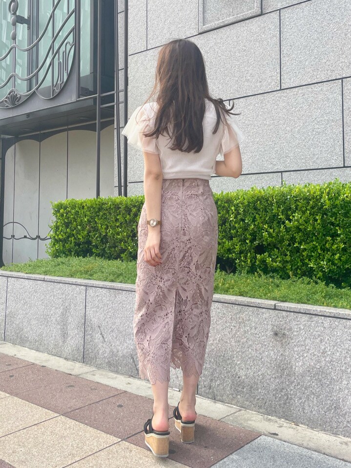 ベージュ系のスカート、ホワイト系のニット/セーターを着用したレディースの春コーディネートの2枚目の写真